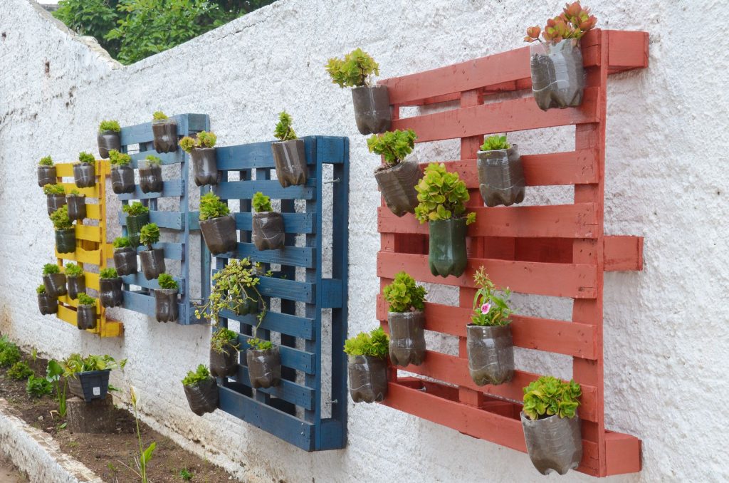 Aqui temos uma horta suspensa usando pallet e garrafas pet para plantar os temperos e flores.