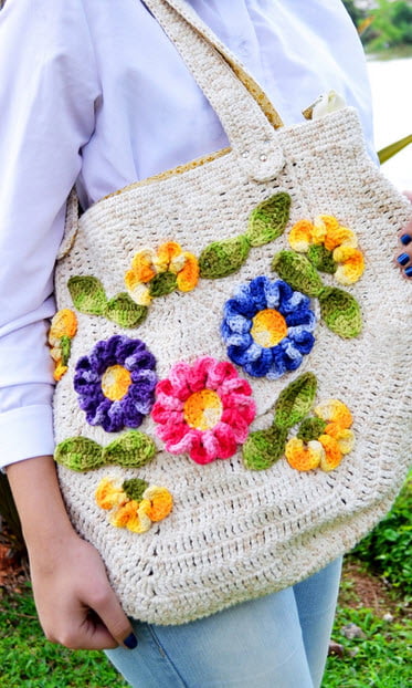 Modelo de Bolsa de Crochê oval com detalhes de flores coloridas.