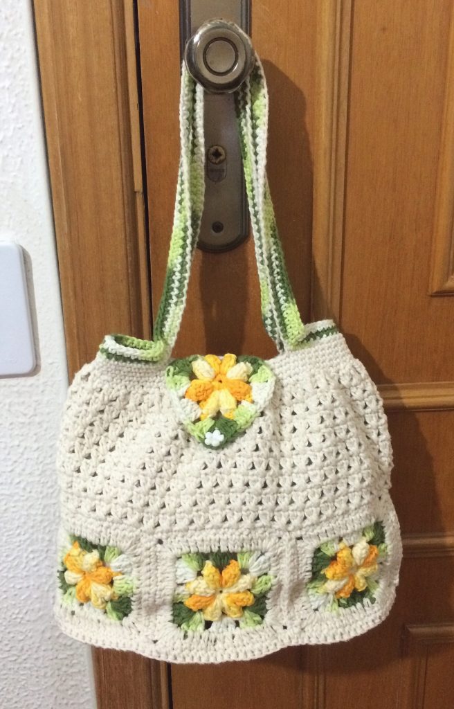 combinar tons de verde na alça na sua bolsa de crochê com flores em tons de amarelo.